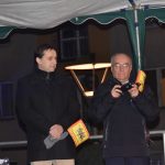 Młody mężczyzna w ciemnym płaszczu i starszy mężczyzna trzymający w rękach telefon komórkowy stoją na scenie.,