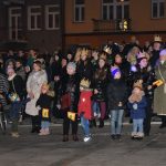 Grupa osób stoi na rynku podczas wydarzenia imprezowego.