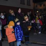 Grupa osób stoi na rynku podczas wydarzenia imprezowego.