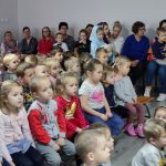 Grupa dzieci siedzi na przedstawieniu w przedszkolu.