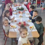 Dzieci siedzą przy stoliku jedzą wieczerze wigilijną.