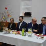 Czterech mężczyzn i kobieta w eleganckich stołach zasiadający przy stole bankietowym.