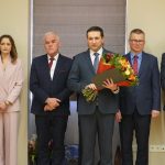 Grupa osób w oficjalnych stroajach i mundurach stojąca na sali konferencyjnej.