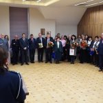 Grupa osób w oficjalnych stroajach i mundurach stojąca na sali konferencyjnej.