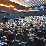 Duża grupa osób różnej płci i wieku siedząca na scenie kinowej. (aktorzy na scenie)