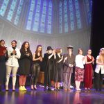 Grupa aktorów na scenie po odegranej sztuce w strojach.