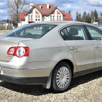 Duże srebrne auto na żwirowym placu w słoneczny dzień.