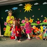 Przedstawienie teatralne na rozleglej sali. Na scenie dzieci w stroju kwiatów, W centrum kobieta w stroju wisony.