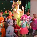 Kobieta ubrana w strój pani wiosny wraz z dziećmi ubranymi w wiosenne stroje.