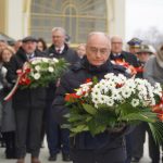 Mężczyzna trzymający bukiet kwiatów. W tle stoi grupa ludzi