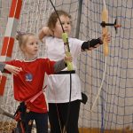 Dwie dziewczynki celujace z łuków na hali.