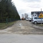 Droga przy której zaparkowane są samochody. W oddali widać maszynę budowlaną