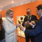 Dwóch mężczyzn w graniturach przekazuje kobietom róże.