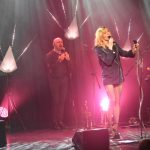 Młoda wokalistka i dwóch dorosłych mężczyzn w czasie występu na scenie.