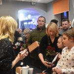 Młoda kobieta podpisuje gadżety dla fanów.