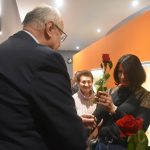 Starszy meżczyzna w garniturze wrecza róże Paniom.