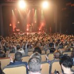 Duża grupa róznej płci i wieku siedząca na sali kinowej.