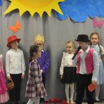 Grupa dzieci w bajkowych strojach podczas występu teatralnego.