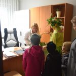 Dzieci i kobieta w stroju wiosny przekazuje upomninki kobiecie w białej koszuli w biurze.