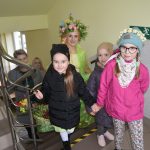 Grupa dzieci i kobiet wchodzący po schodach. Jedna z kobiet ubrana jest w strój reprezentujący wiosnę.