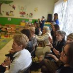 Grupa dorosłych oglądajacy pokaz taneczny dzieci na salce.