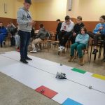 Chłopiec obsługuje zdalnie małego robota. Przygląda mu się grupa młodzieży.