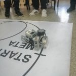 Mały robot leżący na szarej macie.