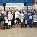 Grupa młodzieży z dyplomami i nagrodami pozująca do zdjęcia.