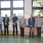 Grupa dorosłych osób, mężczyzn i jednej kobiety stojacych na sali gimanstycznej.