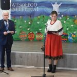 Kobieta w ludowym stroju i mężczyzna w garniturze przemawiający przez mikrofon