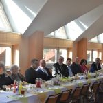 Grupa ludzi siedząca przy zastawionym stole.