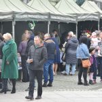 Duża grupa osob na kiermaszu wielkanocnym ogląda stoiska kiermaszu wielkanocnego.