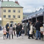 Duża grupa osob na kiermaszu wielkanocnym ogląda stoiska kiermaszu wielkanocnego.