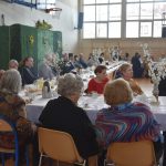 Grupa ludzi siedząca przy zastawionym stole