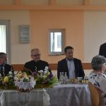 Grupa 4 mezczyn i kobieta zasiadajacy przy rozległym stole na sali.