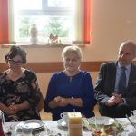 Dwie kobiety i męzczyzna zasiadajacy za zastawionym stole na sali.