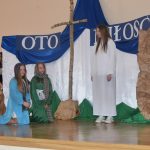 Grupa dzieci na przedstawieniu jasełkowym na scenie na sali.