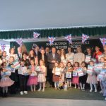 Grupa dzieci i dorosłych pozujacych do zdjecia z dyplomami.