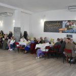 Sala z w której siedzą ludzie przy zastawionych stołach.