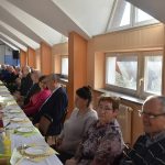 Grupa ludzi siedząca przy zastawionym stole