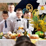 Grupa dzieci w odświetnych strojach na sali gimanstycznej w czasie przedstawienia wielkanocnego.