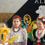 Grupa dzieci w odświetnych strojach na sali gimanstycznej w czasie przedstawienia wielkanocnego.