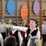 Grupa dzieci w odświetnych strojach na sali gimanstycznej w czasie przedstawienia wielkanocnego.