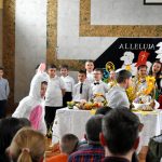 Grupa dzieci w odświetnych strojach na sali gimanstycznej w czasie przedstawienia wielkanocnego.