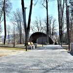 Alejka z kostki brukowej w parku. W tle budynek amfiteatru