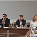 Trzech mężczyzn w garniturach i kobieta siedzą przy stole