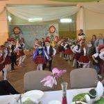 Występ dzieci w stojach ludowych na sali. W tle stoły i goście.