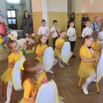 Występ dzieci wuroczystych strojach na sali. W tle stoły i goście.