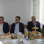 Czterech meżczyn w garniturach zasiada przy zastawionym stole.