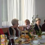 Grupa kobiet zasiadająca przy długim zastawionym stole.